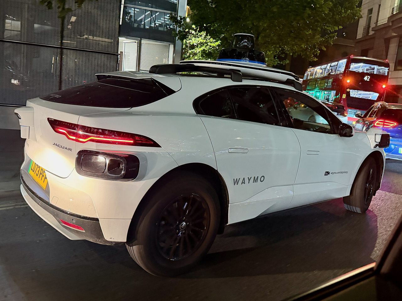 Waymo autonomous car with LiDAR and camera sensors on the roof.